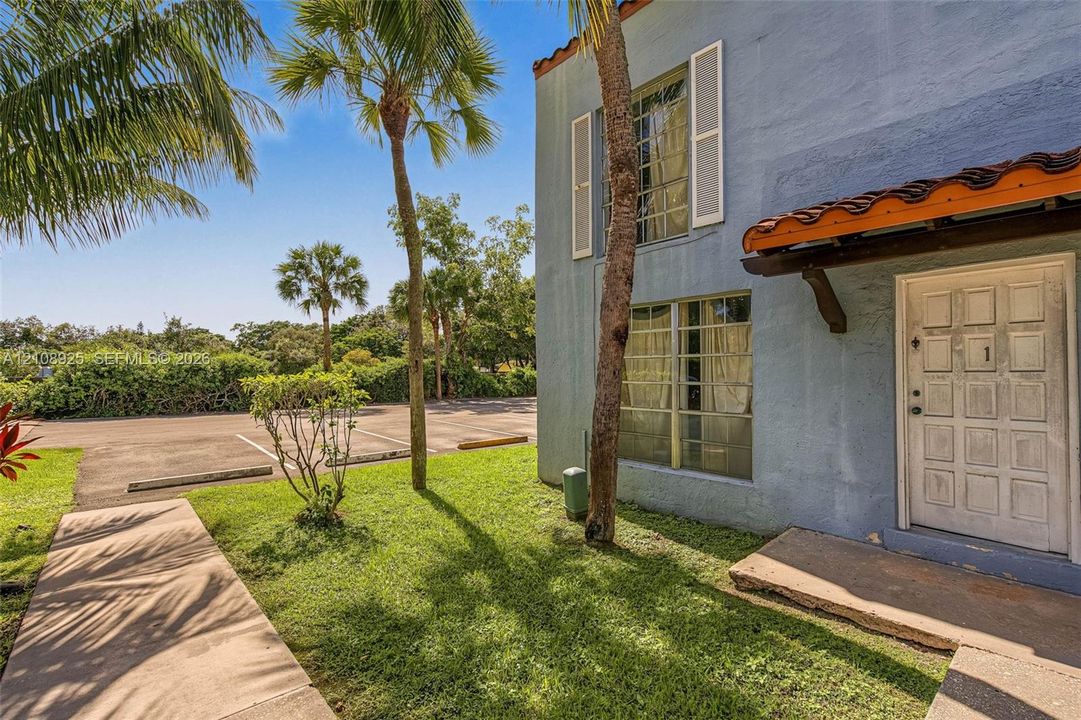 Stucco exterior featuring mission-style clay tile roof accents, multi-pane windows with operable shutters, and a paneled entry door