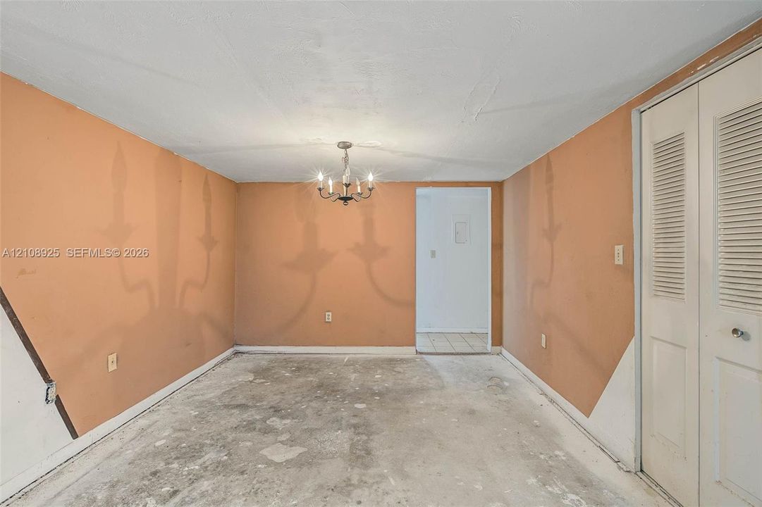 Room featuring a decorative multi-arm chandelier and louvered double closet doors