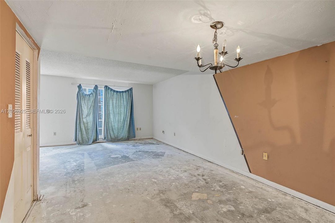 Interior space featuring a multi-arm candle-style chandelier, textured ceiling finish, and louvered bifold closet door