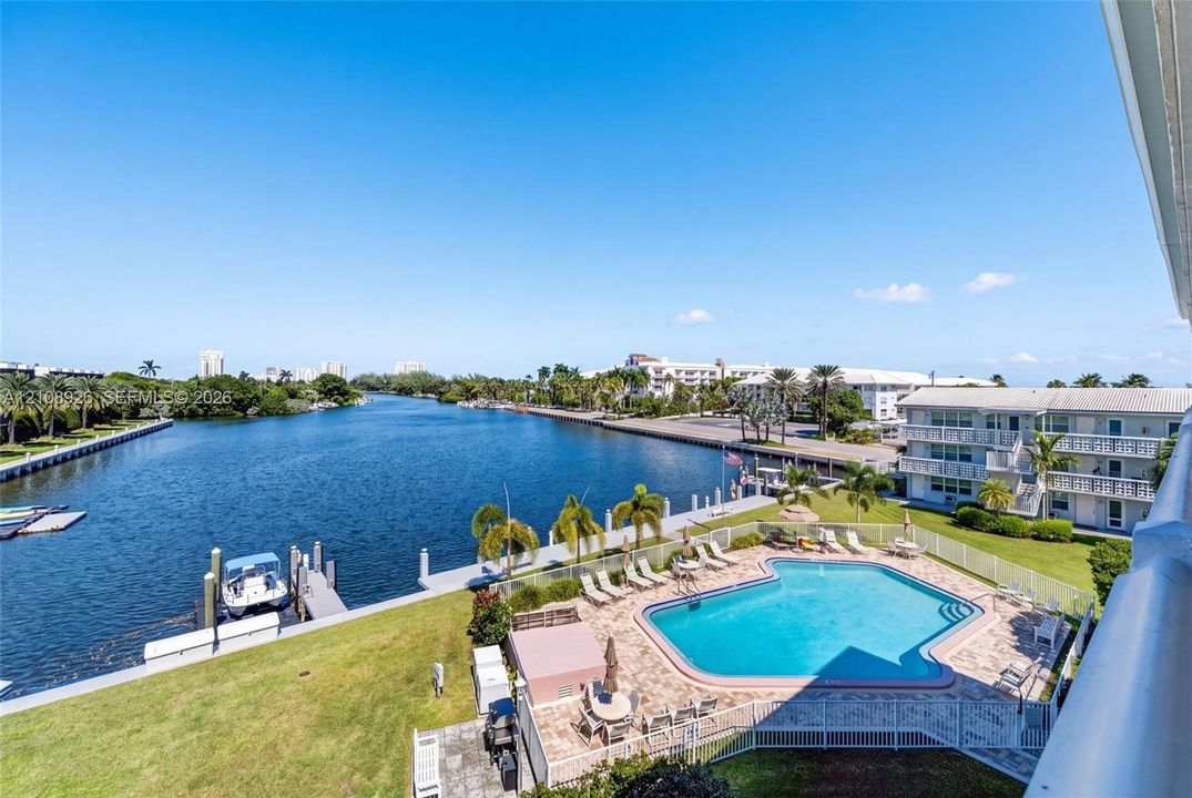 Waterfront property featuring a swimming pool, paved patio, private dock, and grass landscape