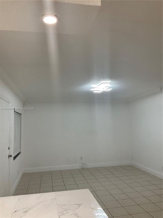 Neutral interior space featuring ceramic tile flooring, modern flush-mount geometric ceiling lighting, recessed lighting, and a white interior door with a blind-fitted window