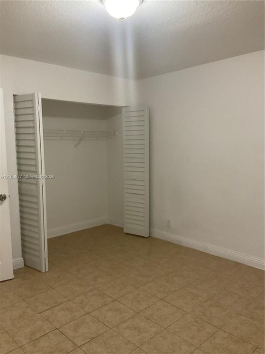 Room featuring tile flooring, a closet with white louvered bi-fold doors, and a ceiling-mounted light fixture