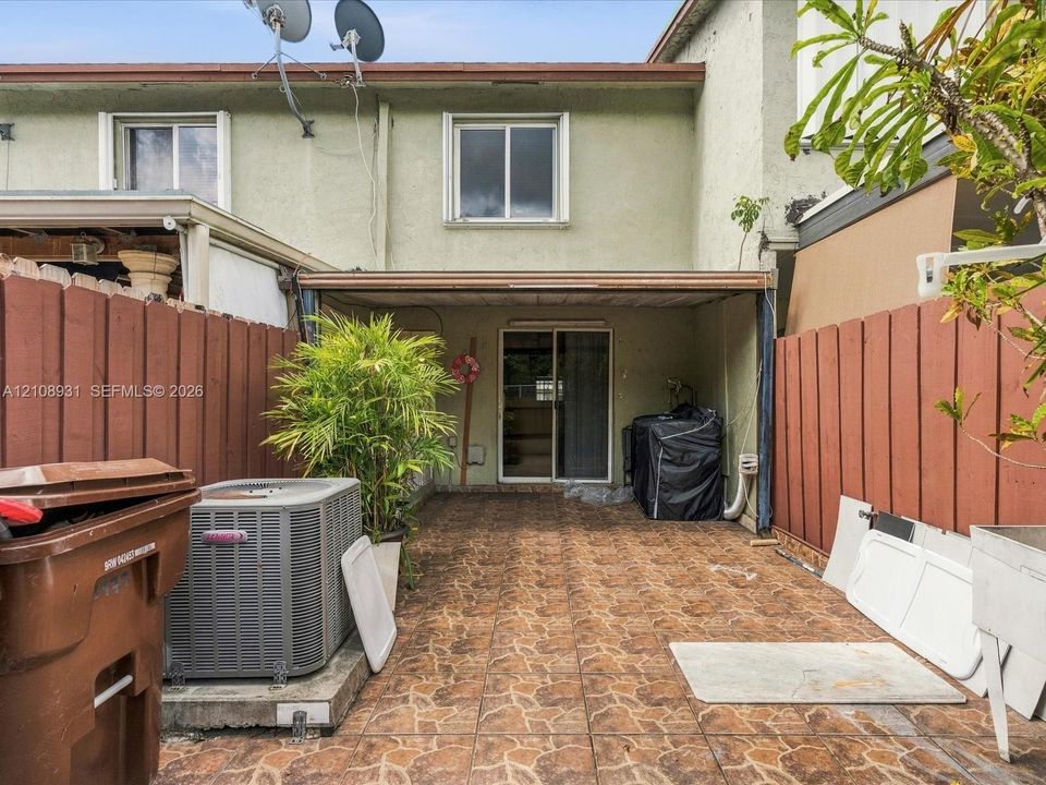 Rear patio featuring tiled flooring and a covered structure enclosed by wood fencing