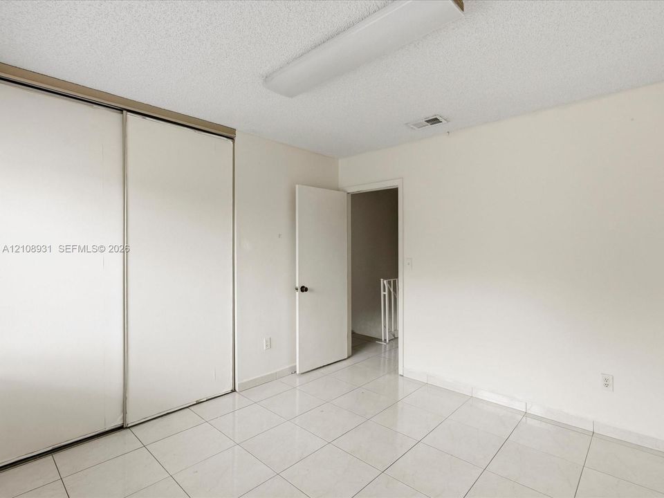 Room featuring ceramic tile flooring, neutral walls, and a large reach-in closet with sliding doors