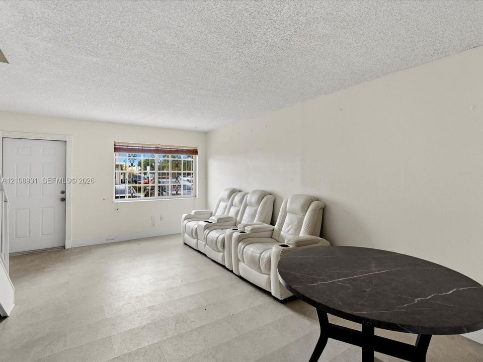 Neutral-toned wall finishes, large-format tile flooring, textured ceiling, and a single-panel entry door