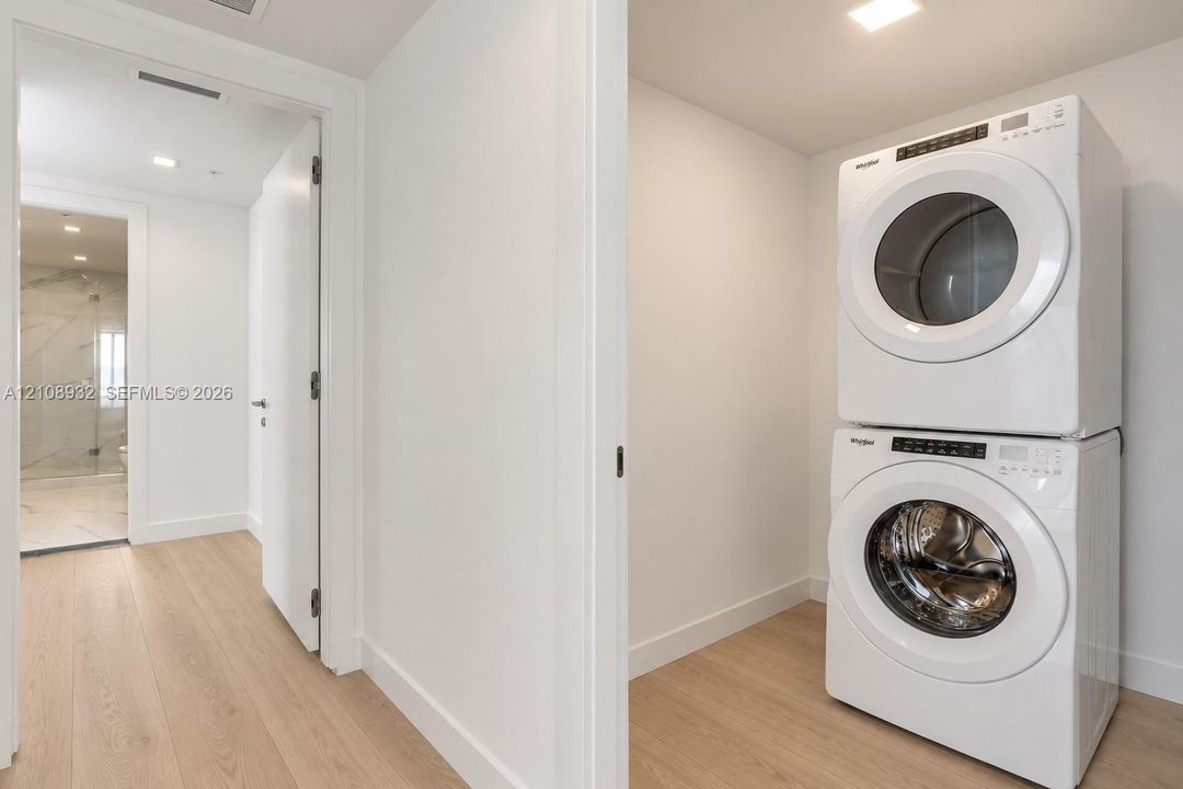 Stacked front-loading washer and dryer, wood-finish flooring, and recessed ceiling lighting