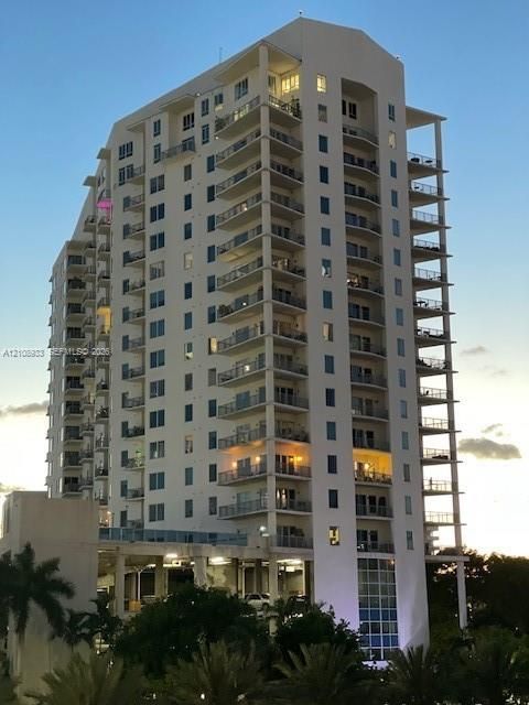 High-rise residential building featuring stacked private balconies, recessed glass windows, and a structured concrete exterior