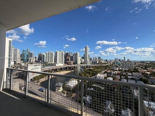 Private balcony featuring a metal grid railing, concrete flooring, and an expansive cityscape horizon