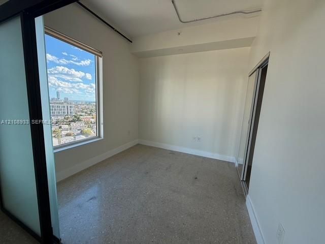 Terrazzo flooring, expansive window with city skyline, exposed industrial-style conduit, and sliding glass panel door