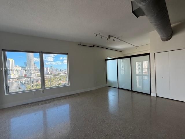 Industrial-style interior featuring polished concrete flooring, exposed ductwork, track lighting, and sliding frosted glass partitions