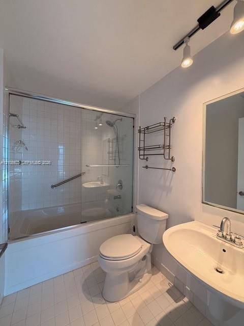 Bathroom featuring a tub-shower combination with sliding glass doors and white tile surround, pedestal sink with chrome dual-handle faucet, frameless wall mirror, and adjustable track lighting