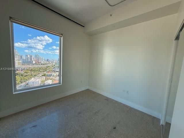 Floor-to-ceiling window featuring city skyline backdrop, neutral wall finishes, and stone-composite flooring