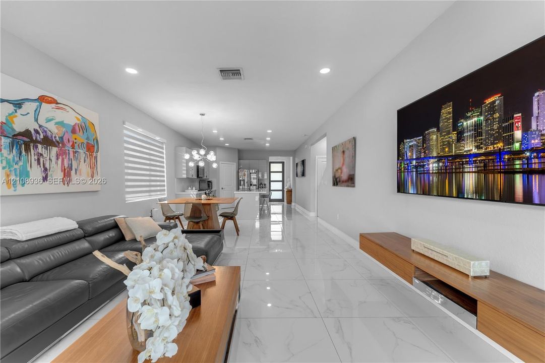 Polished tile flooring, recessed lighting, wall-mounted wood-finish cabinetry, and multi-light pendant fixture
