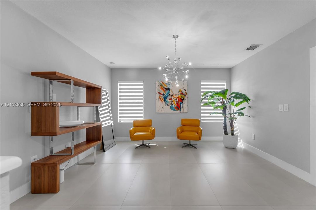 Spacious room featuring neutral tile flooring, dual windows with tiered shades, and a modern sputnik-style chandelier