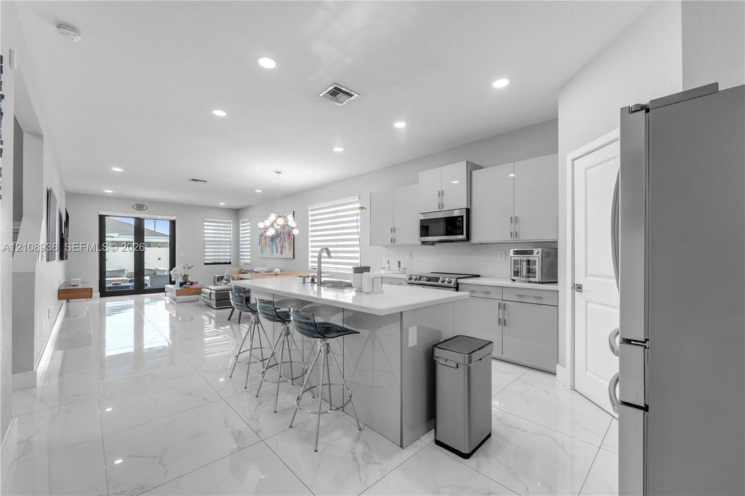 Kitchen featuring large-format tile flooring, flat-panel cabinetry, a central island with a quartz countertop, and stainless steel appliances