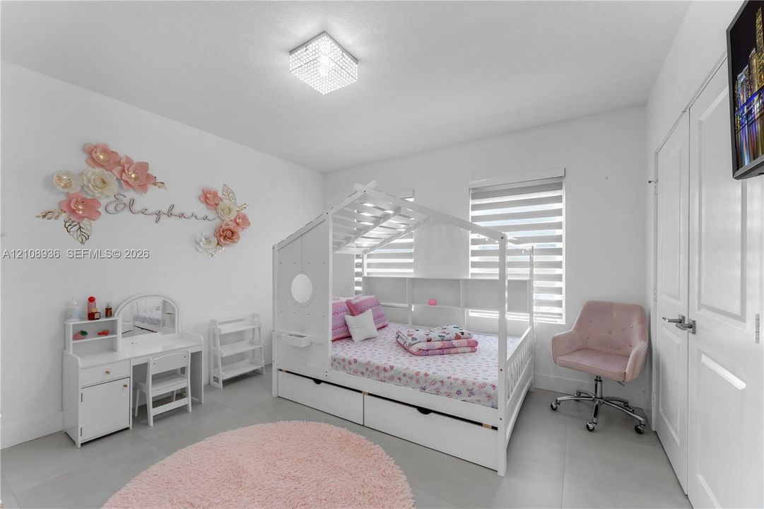 Neutral wall finishes, light-toned tile flooring, square flush-mount crystal-style light fixture, and dual-layered cellular shade blinds