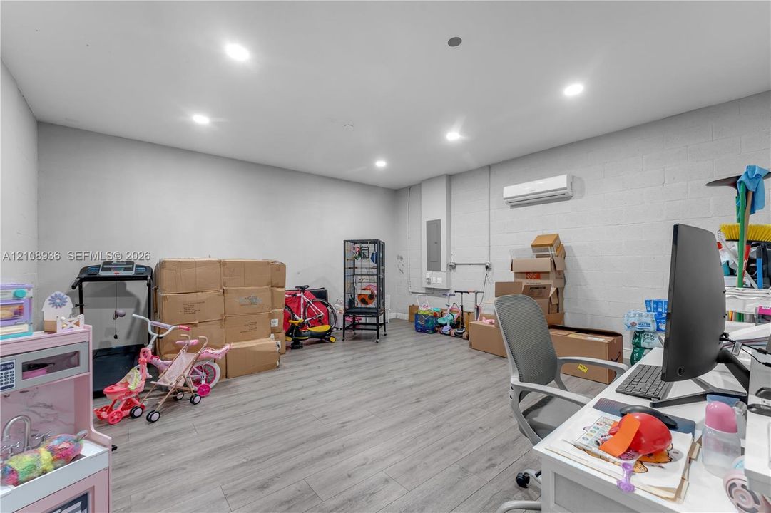 Interior space featuring wood-finish flooring, painted masonry walls, recessed lighting, and a wall-mounted climate control unit