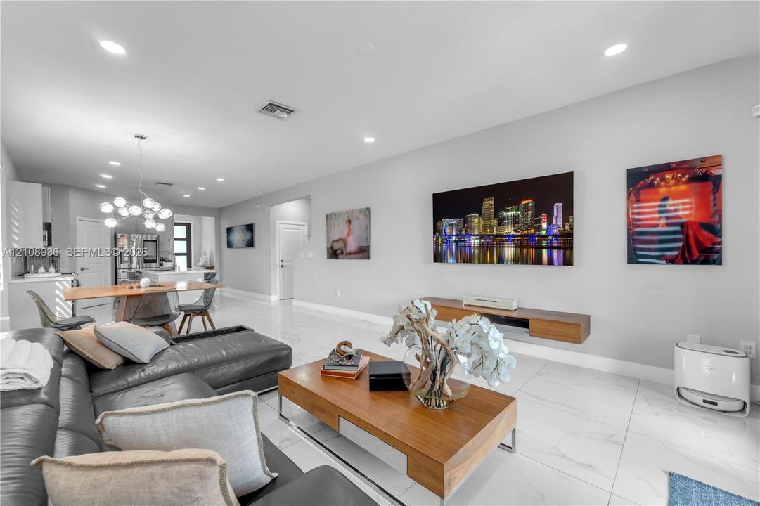 Open floor plan featuring polished tile flooring, recessed lighting, a modern multi-globe chandelier, and a wall-mounted wood-finish media console