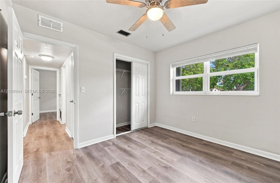 Wood-finish flooring, multi-panel doors, ceiling fan with integrated lighting, and dual-pane horizontal sliding window