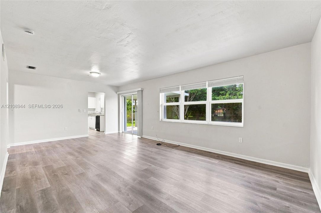 Living area featuring wood-finish flooring, neutral walls, large picture windows, and sliding glass doors