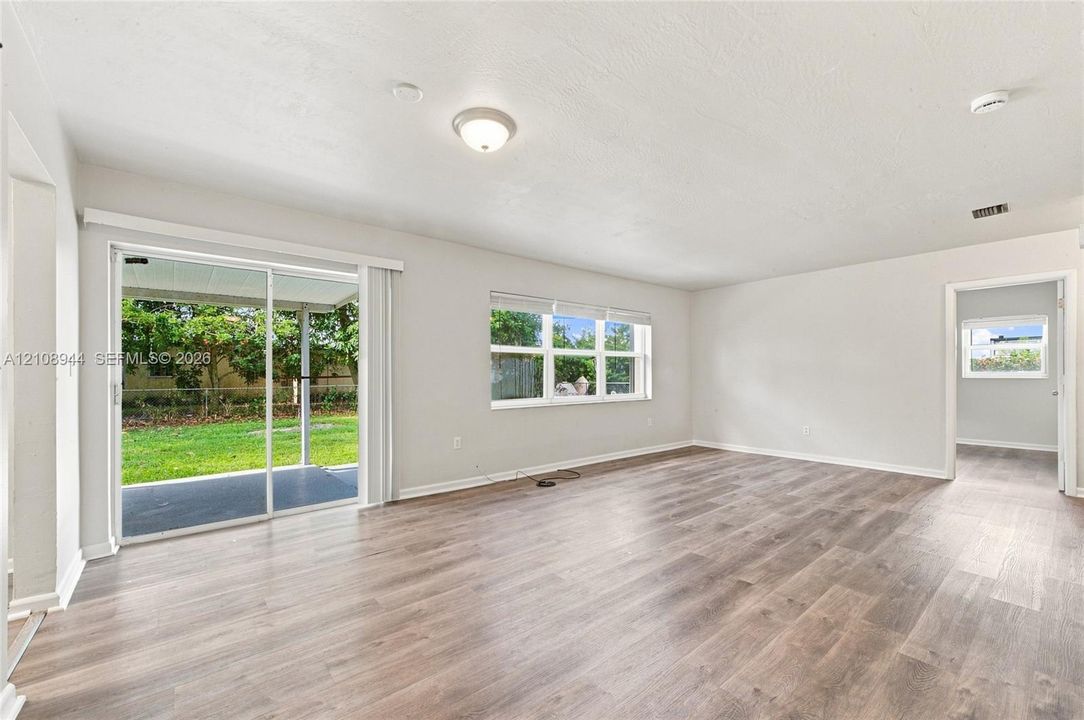 Living area featuring wood-finish flooring, neutral interior paint, glass sliding door, and multi-pane windows