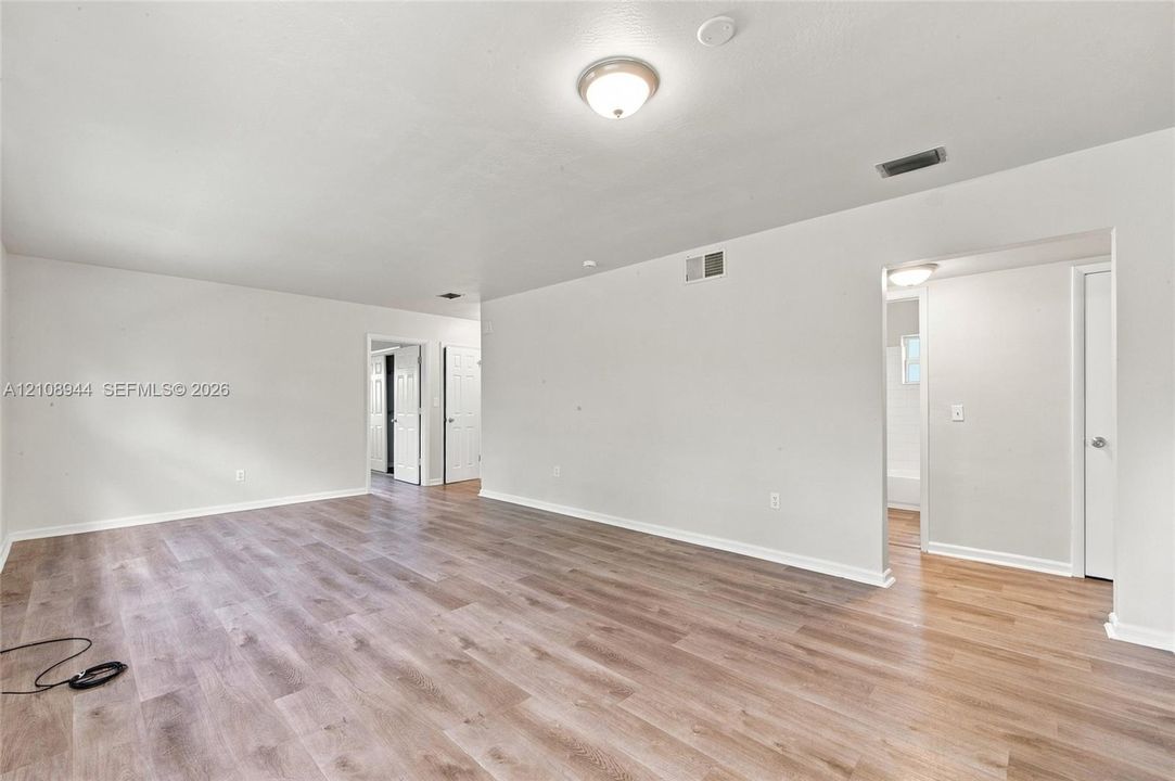 Neutral-toned interior featuring wood-finish flooring, crisp white walls, and a recessed ceiling lighting fixture