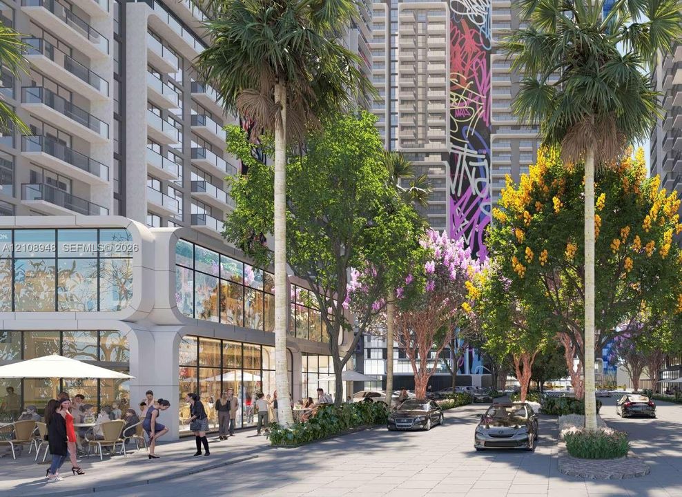 Modern building exterior featuring floor-to-ceiling glass paneling, curved architectural detailing, mature palm trees, landscaped grounds, and paved walkways