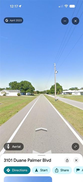 Paved street with grass lawns and mature trees