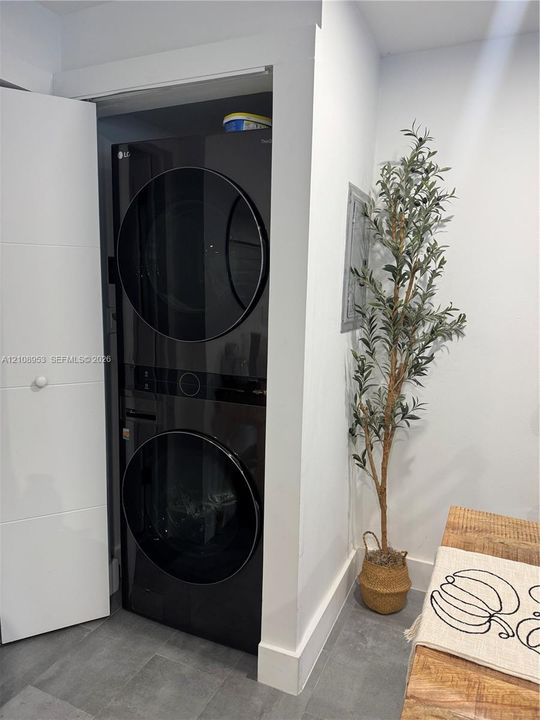 Built-in black stackable washer and dryer unit with a high-gloss finish, recessed within a dedicated enclosure