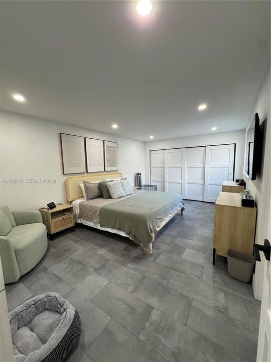 Large-format gray tile flooring, recessed ceiling lighting, and sliding multi-panel closet doors