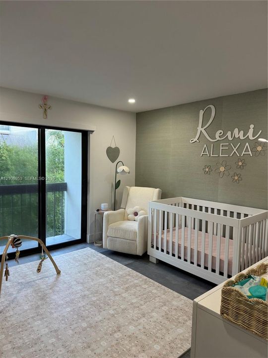 Room featuring a textured olive-toned accent wall, sliding glass door with black framing, and dark wood-finish flooring