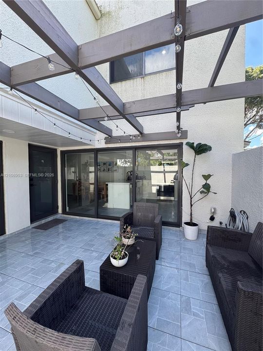 Outdoor patio featuring tile flooring, a pergola, and large multi-panel sliding glass doors