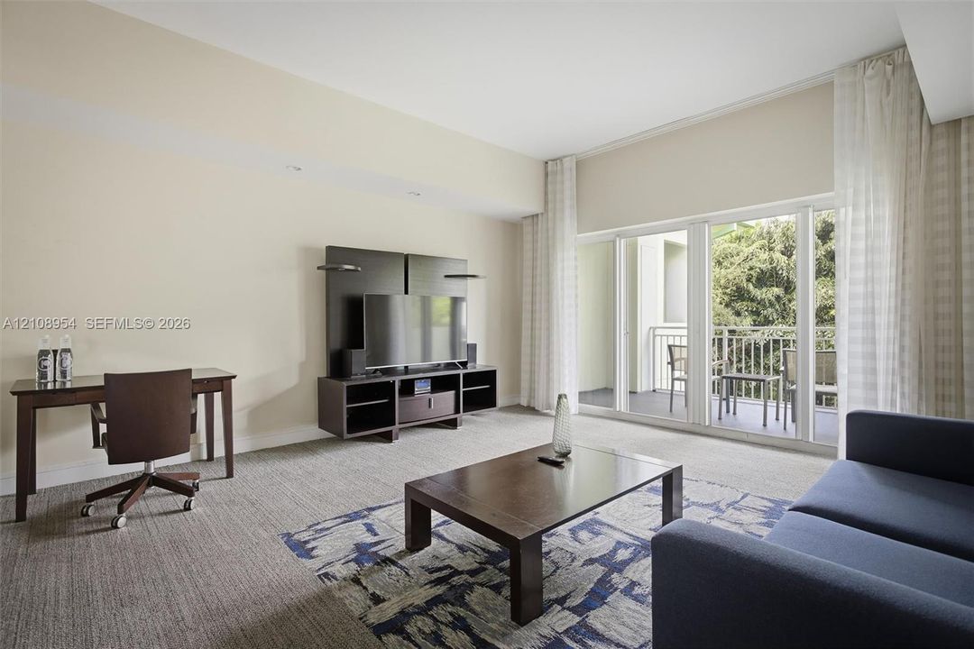 High ceilings featuring recessed lighting, expansive glass sliding doors, and a private balcony with metal railing
