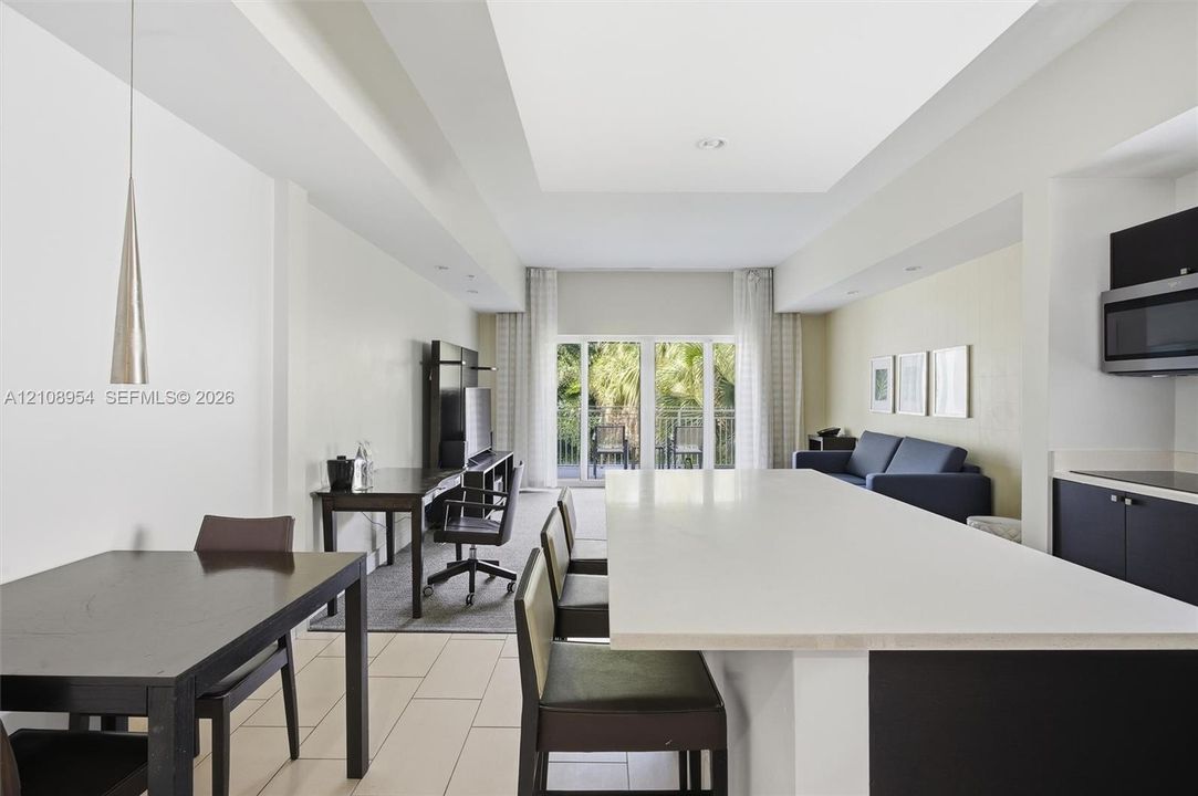 Open-concept interior featuring a center island with a stone countertop, recessed ceiling lighting, tile flooring, and glass paneled doors providing outdoor access