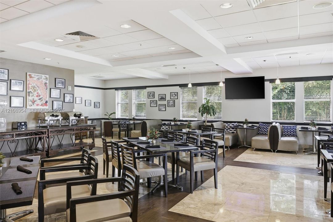 Large common space featuring recessed ceiling lighting, multi-tone stone and wood-finish flooring, and expansive windows with horizontal blinds