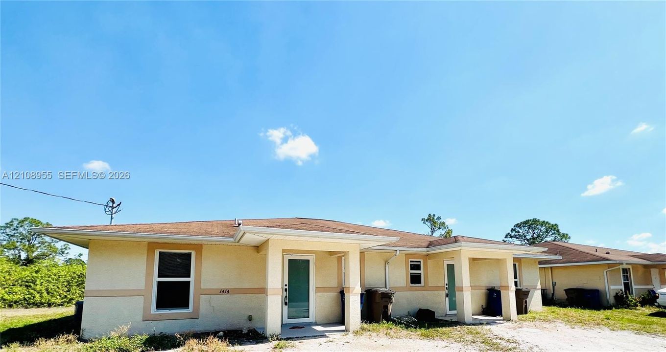 Single-story stucco exterior featuring a hipped roofline, covered entry porticos, and rectangular windows with decorative trim