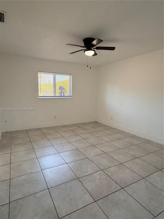 Neutral-toned tile flooring, white wall finishes, and a central ceiling fan with integrated lighting
