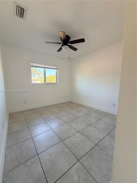 Interior room featuring large-format neutral tile flooring, a multi-blade ceiling fan with integrated lighting, and a single-pane window