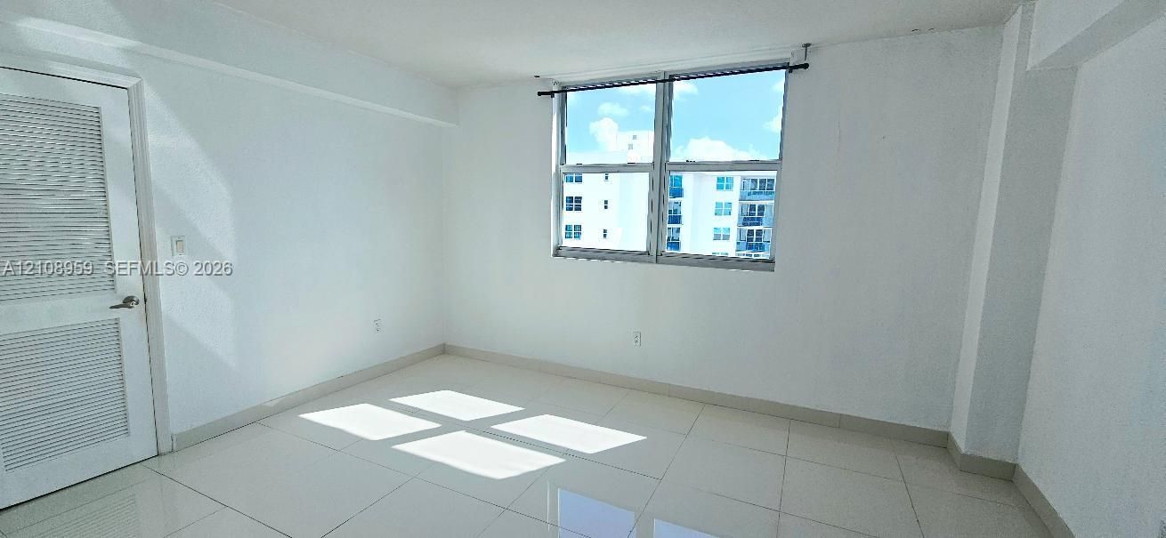 Interior space featuring large-format tile flooring, bright neutral walls, and a louvered closet door