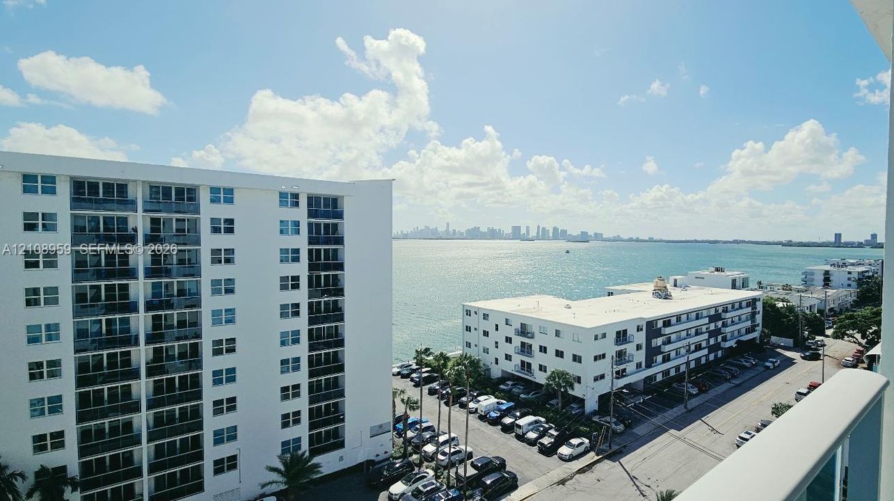 Private balcony with a metal railing overlooking the bay and distant skyline