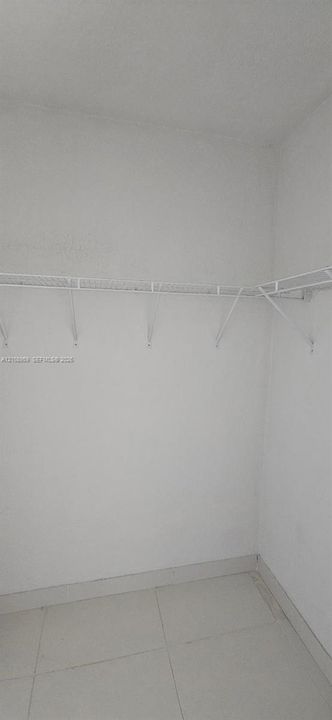 Closet featuring white wall-mounted wire shelving and neutral tile flooring