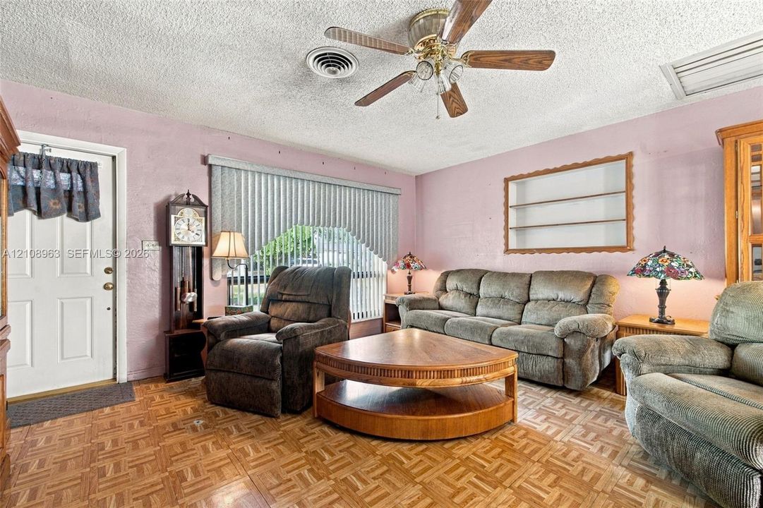 Parquet wood-finish flooring, ceiling fan with integrated lighting, built-in wall niche, and vertical blinds