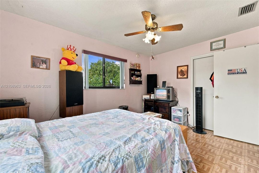 Bedroom featuring a multi-light ceiling fan, sliding window, and parquet flooring