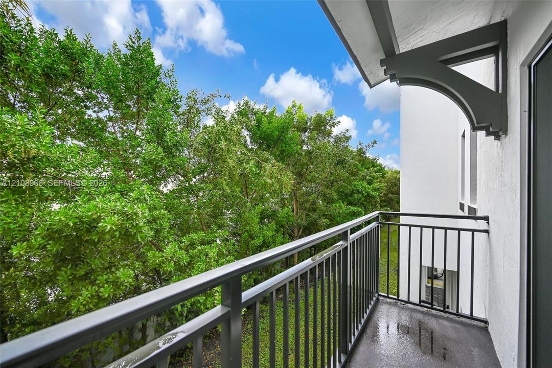 Covered balcony featuring black metal railings, white stucco exterior walls, and decorative structural corbels