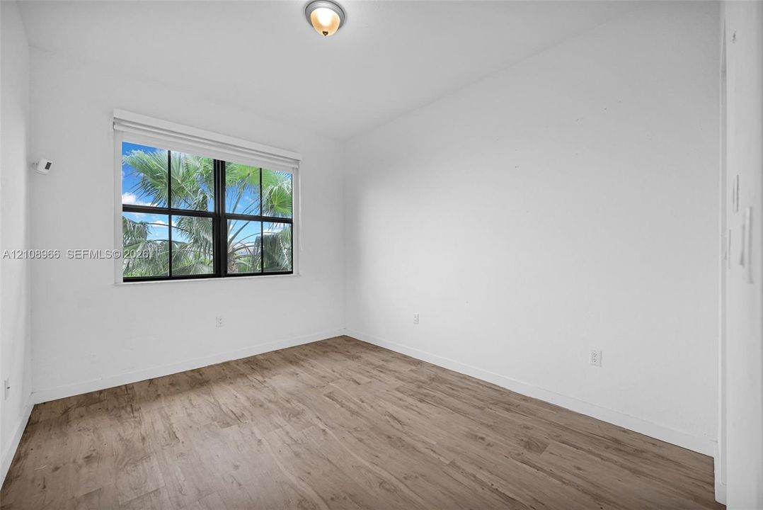 Wood-finish flooring, multi-pane window with black framing, and neutral wall tones