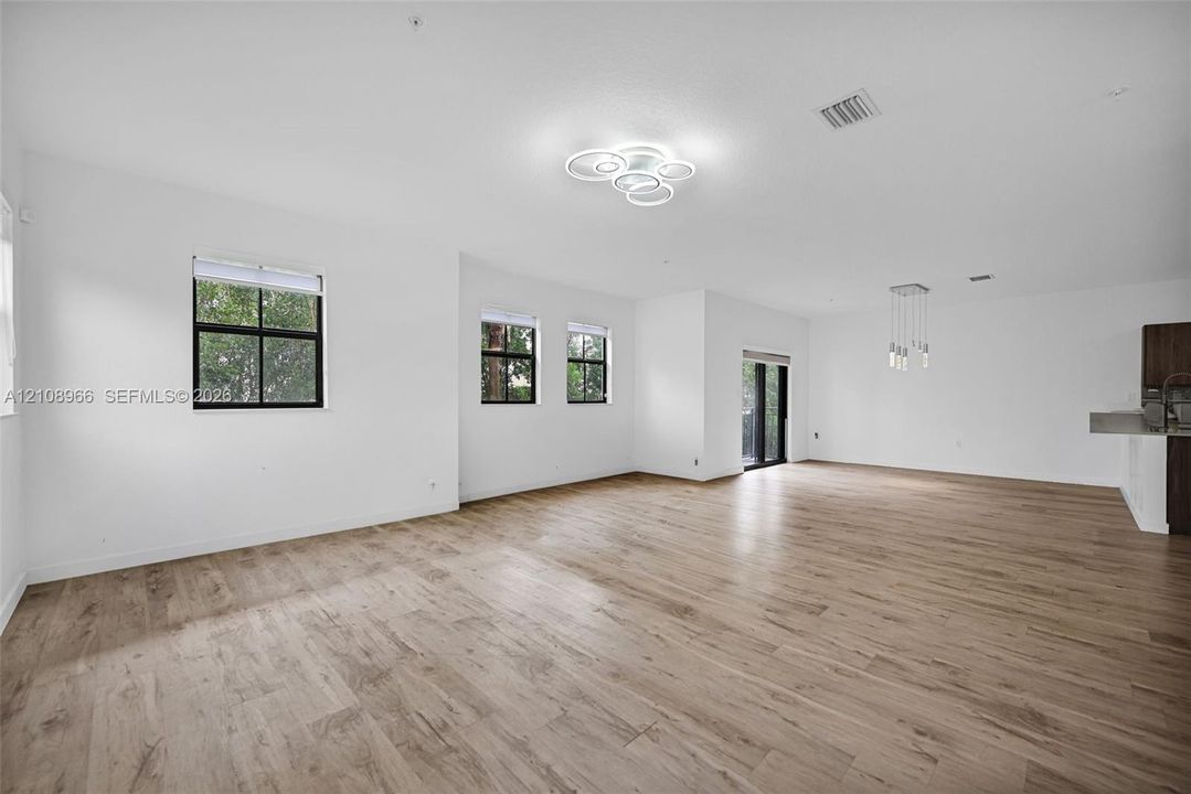 Open floor plan featuring wood-finish flooring, multi-light modern ceiling fixtures, and expansive windows