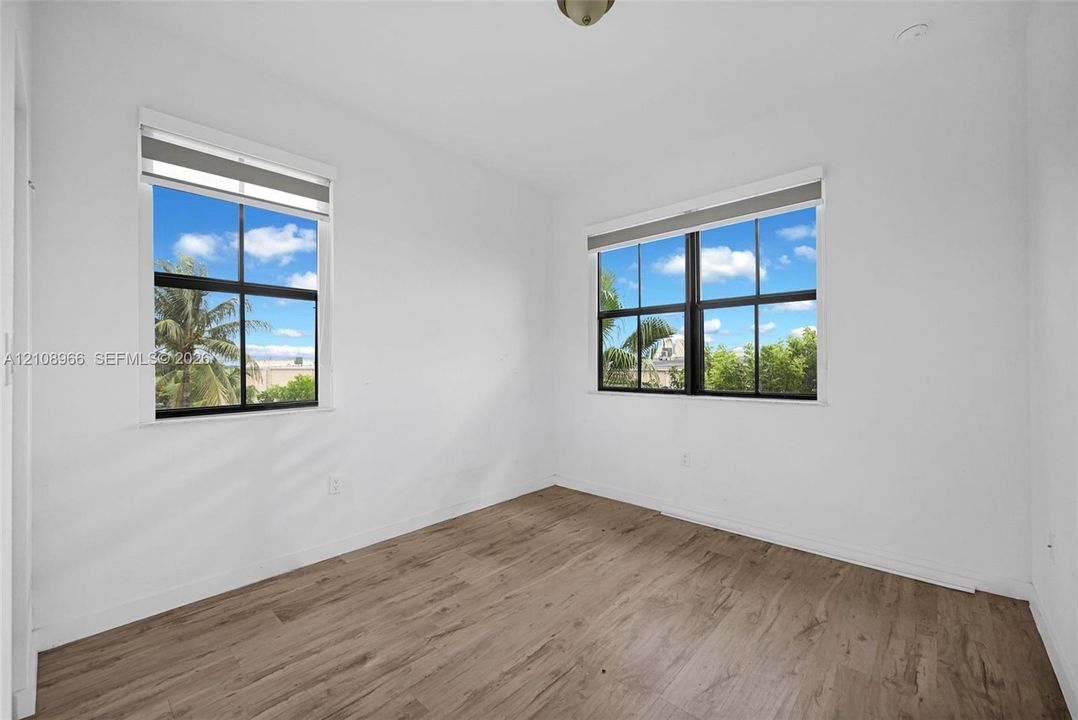Room featuring wood-finish flooring, dual windows with black frames, and neutral wall tones