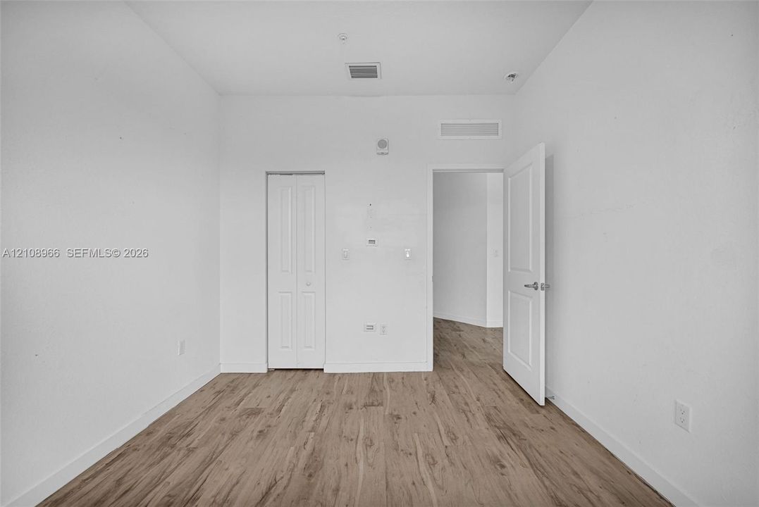 Room featuring wood-finish flooring, two-panel interior doors, and a bi-fold closet door