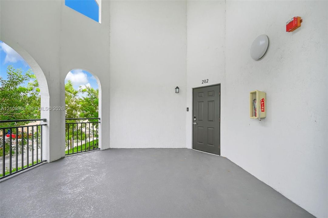 Covered exterior entryway featuring arched openings, metal railing, and high ceilings