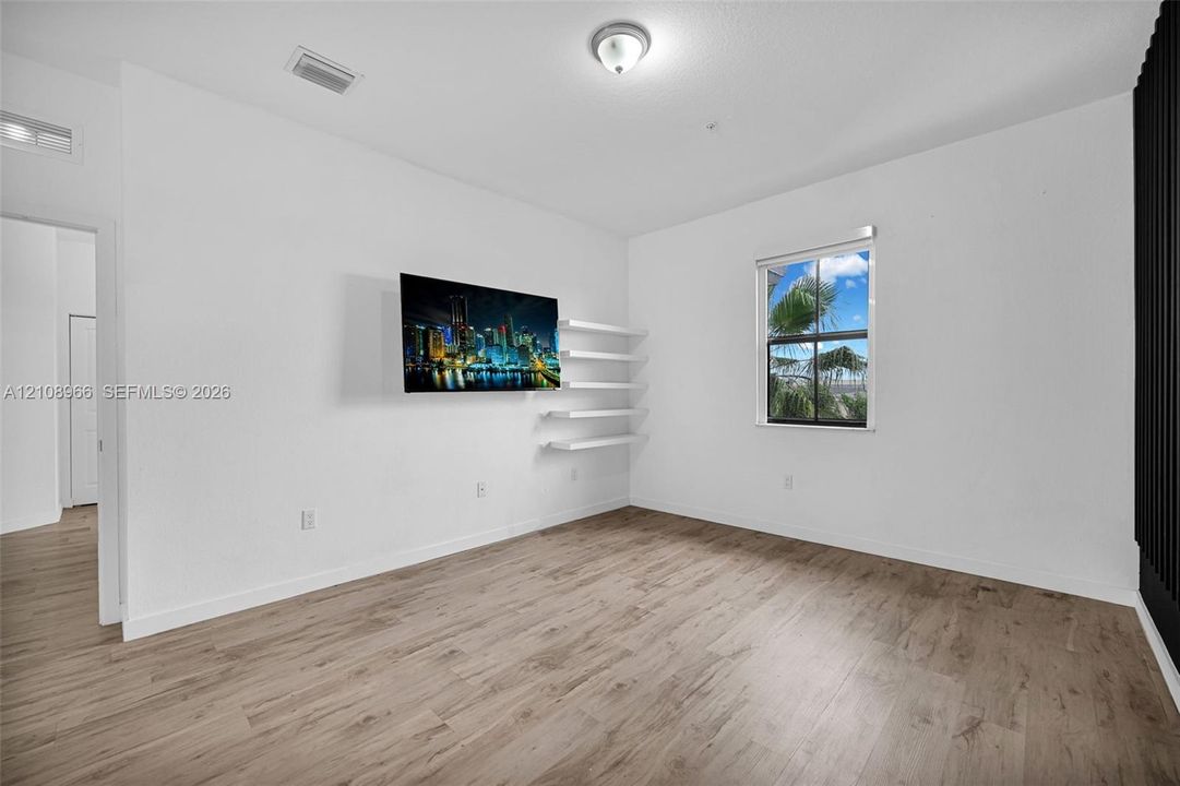 Wood-finish flooring, built-in wall shelving, and a single-hung window with a neutral frame